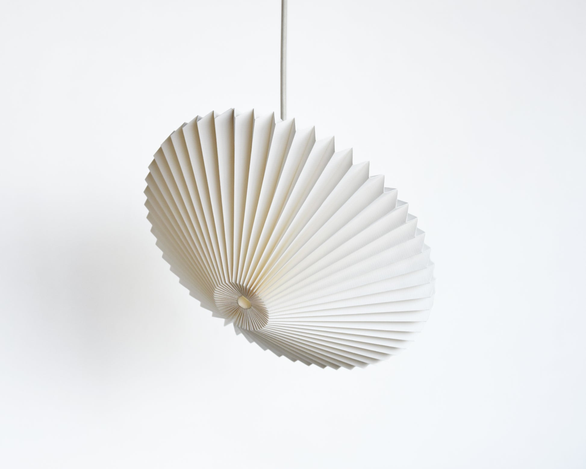 A white pendant lamp made of paper, shaped like a flying saucer